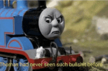 thomas the tank engine is making an angry face while sitting on the tracks .