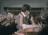 a man and a woman are dancing in front of a band of violins