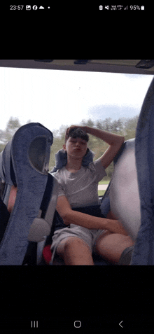 a phone screen shows a man sitting in a bus with his head on a pillow