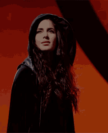 a woman wearing a black cape with a hood is smiling