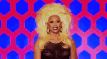 rupaul is wearing a wig and earrings and smiling .