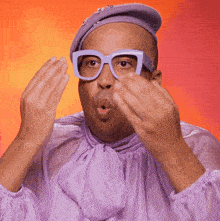a man wearing glasses and a purple shirt is making a face