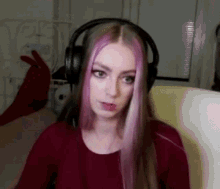 a woman with pink hair is wearing headphones while sitting in a chair .