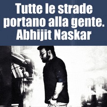 a man is standing in front of a sign that says tutte le strade portano alla gente