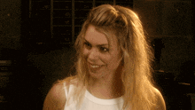 a woman with blonde hair is smiling and wearing a white top
