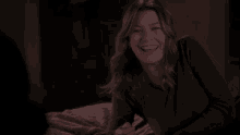 a woman is smiling while laying on a bed in a dark room