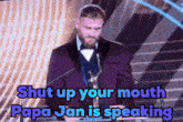 a man in a purple suit is giving a speech and the words shut up your mouth papa jan is speaking