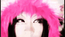 a close up of a woman wearing a pink wig and making a funny face .