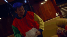 a man wearing a colorful sweater is smiling and holding a piece of paper