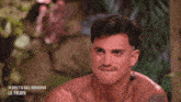 a shirtless man with a tattoo on his arm is sitting in a jungle .