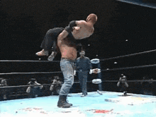 a wrestler is carrying another wrestler on his back in a wrestling ring