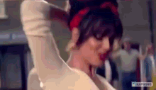 a woman wearing a red headband and a white shirt is dancing in a room .