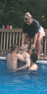 a group of people are swimming in a pool with a woman standing on a chair