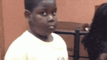 a young boy is making a funny face while standing in front of a woman .