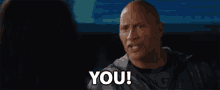 a bald man is pointing at a woman and says " you "
