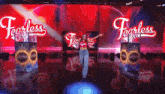 a woman stands on a stage in front of a large screen that says fearless