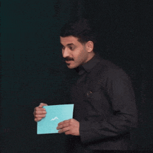 a man in a black shirt is holding a piece of paper in his hand