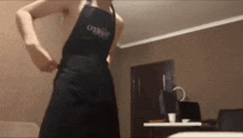 a man in an apron is standing in a living room .