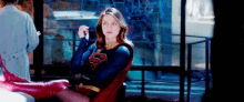 a woman in a superman costume is sitting in a chair in front of a window .