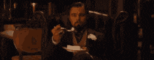 a man in a suit and tie is sitting in a chair and talking on a phone