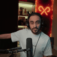 a man wearing headphones stands in front of a microphone in front of a sign that says ' x ' on it