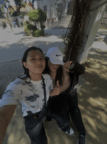 a girl wearing a nike hat is giving a thumbs up next to another girl