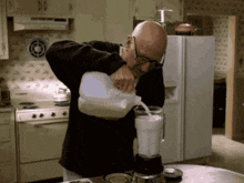 a bald man pouring milk into a blender