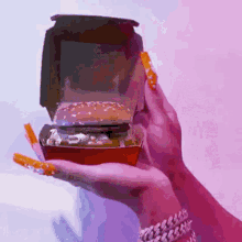 a woman is holding a hamburger in her hand .