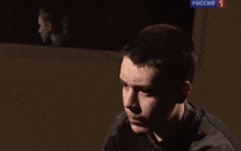a man is sitting in front of a screen that says " russia " on it