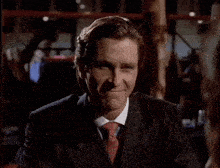 a man in a suit and tie is smiling and looking at the camera