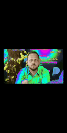 a man in a green shirt is pointing at something in front of a sign that says ao ceixa