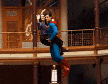 a man dressed as superman is carrying a woman in his arms