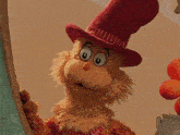 a cat in a hat is looking out a window