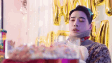 a man is blowing out a candle on a cake at a birthday party .