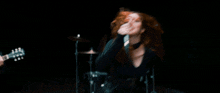 a woman with red hair singing into a microphone