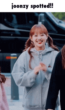 a girl in a hoodie is smiling and says ' joonzy spotted '