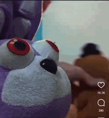 a person is holding a stuffed animal with red eyes .