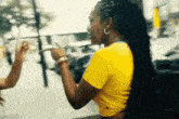 a woman in a yellow shirt is pointing at another woman 's hand .