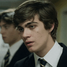 a young man in a suit and tie looks at the camera .