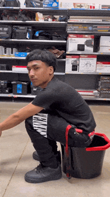 a man squatting on a bucket in a store with a t-shirt that says ' calvin klein ' on it