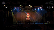 a woman is dancing on a stage in front of a bunch of lights
