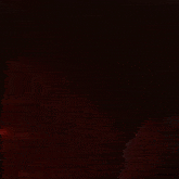 a person is standing in the dark with a red light behind them .