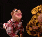 a puppet wearing glasses and a plaid shirt is talking to a leopard