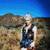a woman in a colorful dress is standing in a field