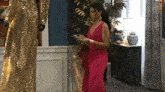 a woman in a pink dress is standing in a room