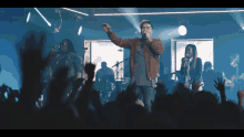 a man sings into a microphone in front of a crowd of people
