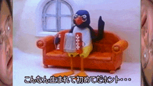 a penguin sitting on an orange couch holding a beer