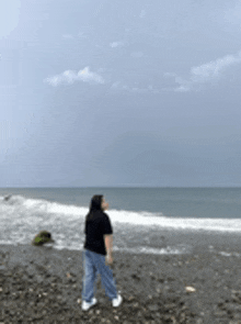 a woman is standing on a beach looking up at the sky .