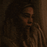 a woman is covering her face with her hands in front of a lamp