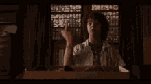 a man with curly hair is sitting in a cardboard box and giving the middle finger .